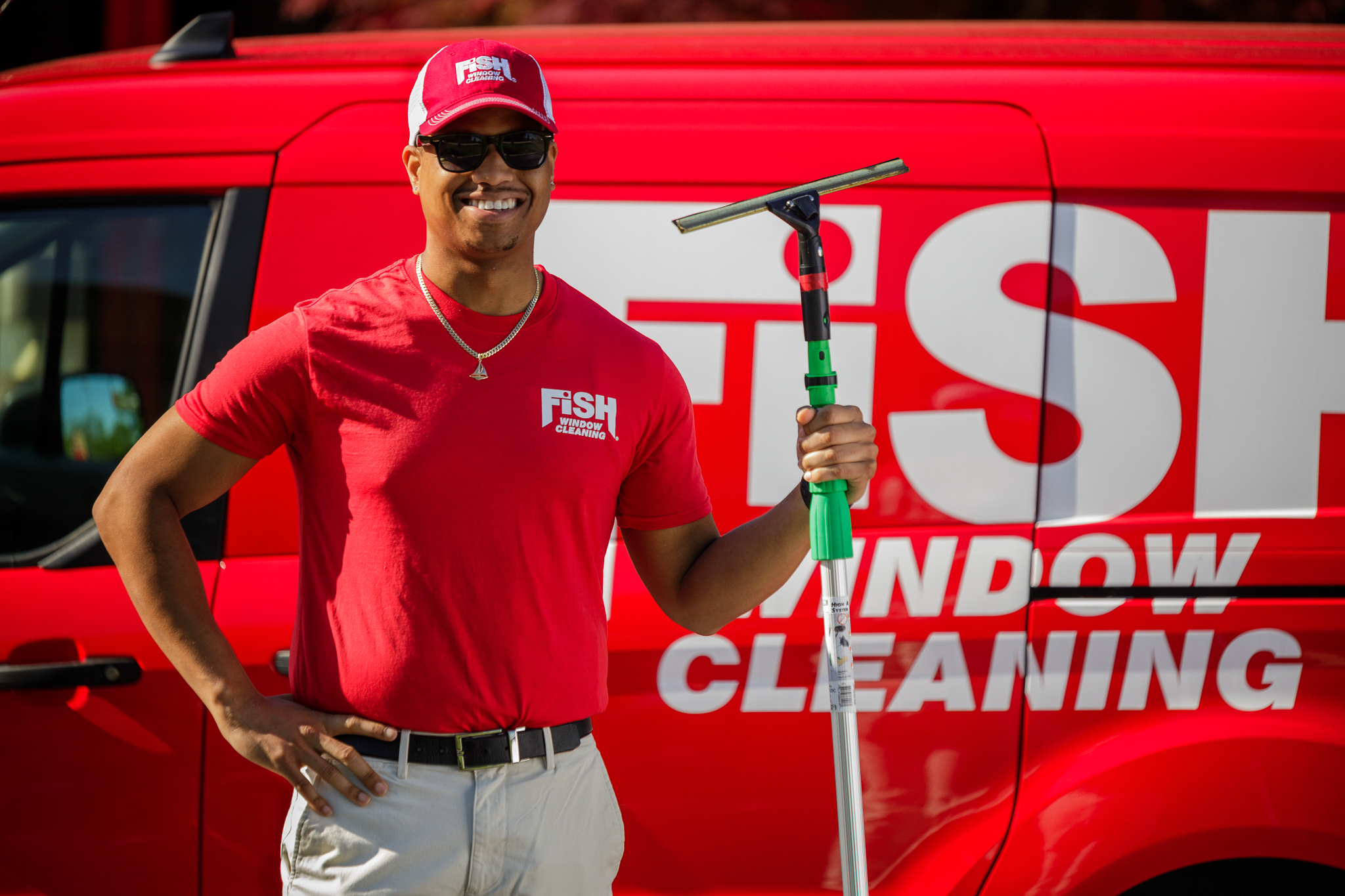 FISH Window Cleaner Holding Pole Next To Logo'd Van